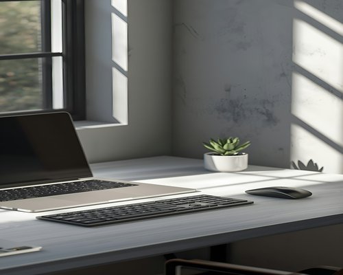 A laptop setup on a desk next to a window with filtered natural tropical daylight